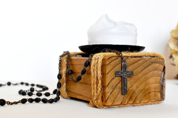 Dark rosary for prayers on a light background, yellow dried flower and wooden candlestick with white candle
