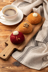 Delicious sweet buns and coffee served on a wooden board with a rustic cloth in a cozy cafe setting