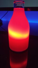 Glowing red liquid in glass bottle on dark surface