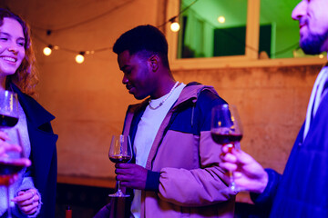 Friends enjoying a lively evening with wine in a cozy venue decorated with string lights