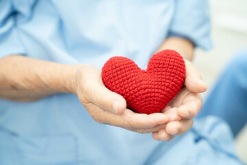 Asian elder senior woman patient holding red heart in hospital.