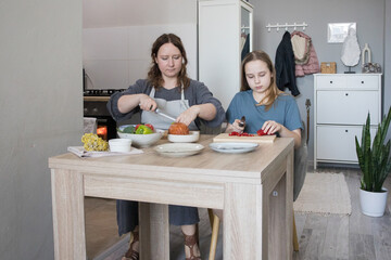 Mother and child daughter cutting vegetables in kitchen