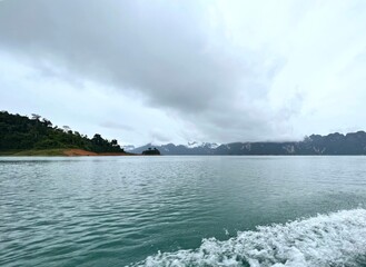 A serene lake scene with cloudy skies and distant mountains, reflecting tranquility and the beauty of nature.