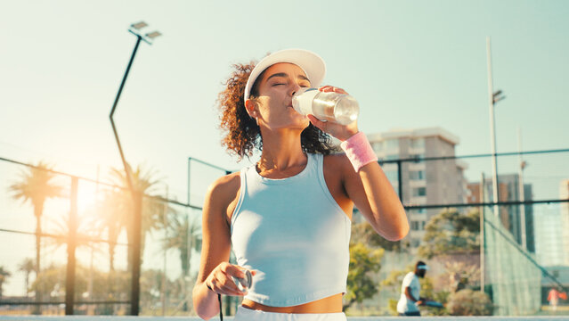 Sports, drinking water and woman on outdoor tennis court for hydration, thirst and wellness on break. Fitness, athlete and person with bottle after training, exercise and workout for padel practice