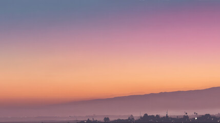 A serene sunset paints the sky in gentle hues of pink and orange over distant mountains and a peaceful cityscape in the early morning light atmosphere.