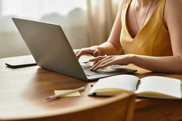 Young beautiful woman working on a laptop at a cozy wooden table during daylight hours