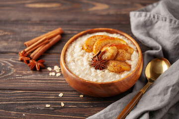 Oatmeal porridge with caramelised apples and bananas in bowl on the table. Homemade healthy breakfast