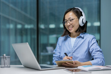 Woman watching online video course, training conference inside office at workplace. Asian Office...