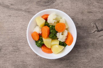 Cooked vegetables in a plate over wooden table