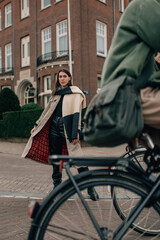 Obraz premium Stylish young woman in a fashionable coat posing on the streets of Amsterdam, lifestyle portrait.