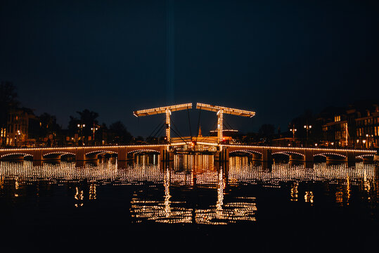 Night view of the illuminated Magere Brug (Skinny Bridge) over Amstel river in Amsterdam, Netherlands.
