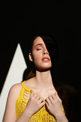 Young beautiful woman basking in sunlight with shadows creating a dramatic effect