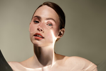 Elegant portrait of a young beautiful woman illuminated by soft light in an artistic setting