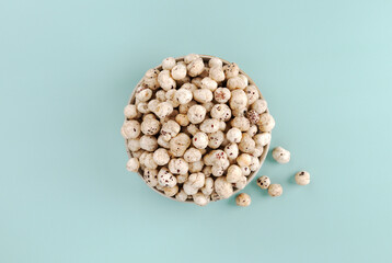 Top view of bowl filled with fox nuts (makhana), a popular Indian snack, on blue background. Top...