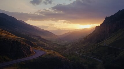 Obraz premium Mountain road winding through valley at sunset. Scenic vista of a winding highway in a valley surrounded by majestic mountains, bathed in golden sunlight as the sun sets