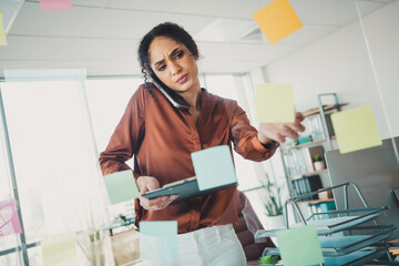 Young businesswoman multitasking in an office setting with sticky notes