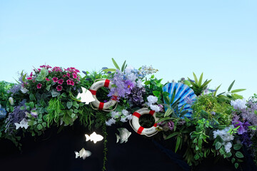 Decor in style of sea travel with fishes, lifebuoy, artificial flowers and leaves. marine style street decorations outdoor. nautical lifestyle objects. Summer sea vacation concept