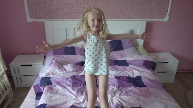 Little Girl  Falls On Bed, girl falls on her back slowly in the room on the bed, cheerful little girl plays in the bedroom