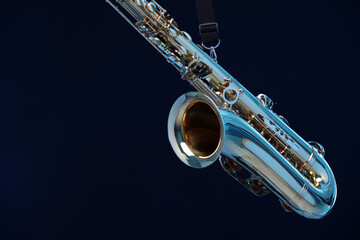 Golden saxophone on dark blue background with smoke, closeup. Space for text