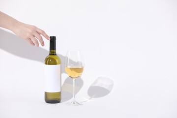 Woman with bottle of wine and glass on white background, closeup. Space for text