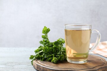 Healthy parsley tea on grey wooden table, space for text. Detox drink