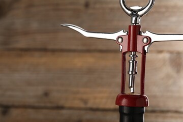 Bottle of luxury wine with corkscrew on wooden background, closeup. Space for text