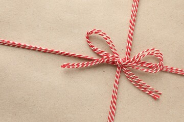 Gift wrapped in kraft paper and bow as background, top view