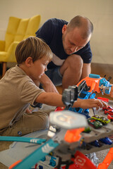 Father and son playing with a toy car track on the floor at home. Fun bonding moment, quality family time, indoor activity on a cozy rug in the living room.