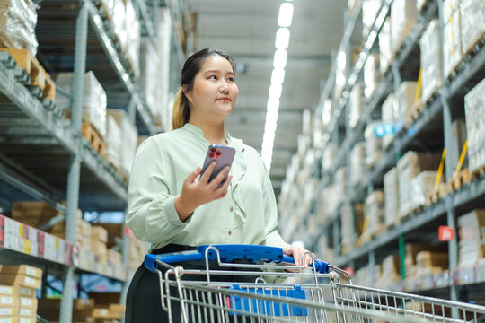 female warehouse manager confidently navigates aisles, managing shipping orders and inventory with her smartphone large storage Female warehouse manager shipping order inventory management