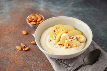 Sweet milky semolina porridge with apples bananas and almonds in a bowl on the table. Healthy children's breakfast.