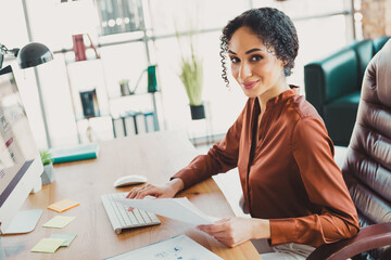 Professional businesswoman working confidently in a modern office with natural daylight and stylish...