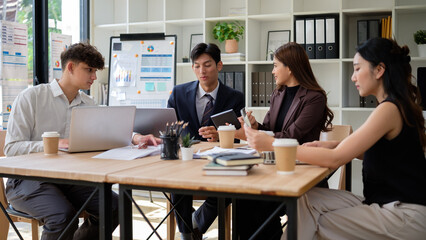 Diverse group of coworkers analyzing data and discussing strategy in modern office.