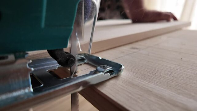 a green jigsaw saws a bright plank, close up slow motion. High quality 4k footage