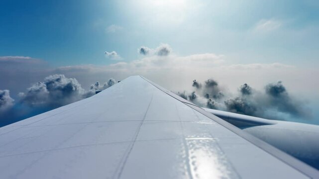 View of an airplane jet wing flying above white clouds and blue sky. Concept of travel and holidays.
