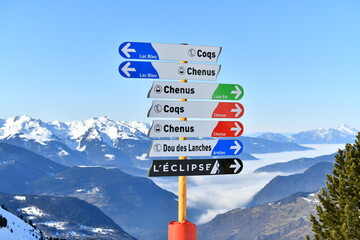 Direction signs on the slopes of Courchevel ski resort showing Chênus and Coqs slopes