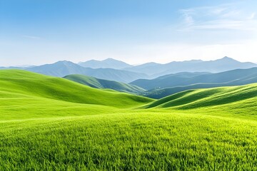 Fototapeta premium Rolling green hills under a clear blue sky with distant mountains