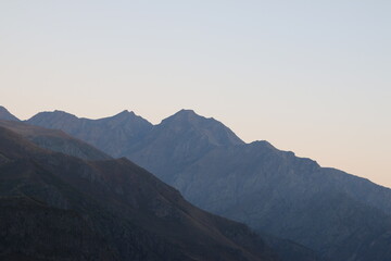 Majestic mountain ridges at twilight with soft pastel sky. Layers of rugged peaks create a sense of depth and tranquility, ideal for travel, adventure, hiking, and serene landscape concepts.