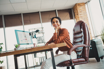 Confident young businesswoman at work in a modern office environment, seated at her desk and...