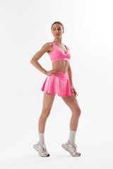 Fitness model poses in bright pink activewear showcasing strength and style in a studio setting