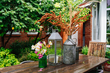 wooden table with lanterns and dried flowers. The yard in the house.