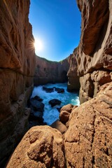 Sunlit Coastal Gorge: Vibrant Ocean Waves Crashing Through Rugged Cliffs