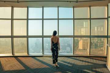 Asian stylish woman enjoying on observation deck and modern glass window in skyscraper at Bangkok