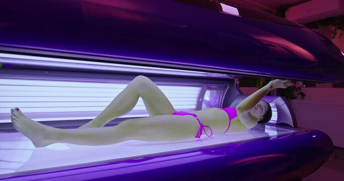 Woman relaxing during a tanning session in a solarium, enjoying therapy for a perfect skin tone