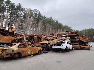 A haunting tableau of rusted, bullet-riddled civilian vehicles stacked in the streets of Irpin,...