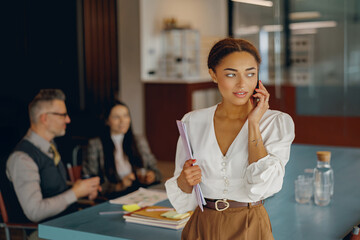 A professional woman is speaking on the phone, engaged in important business discussions with colleagues