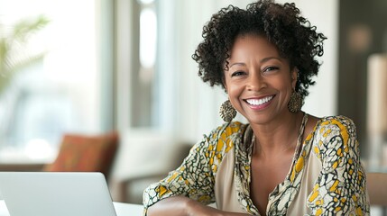 A thoughtful older woman with long, dark dreadlocks sits at a dining table, resting her chin on her hand and gazing upward, smiling slightly.