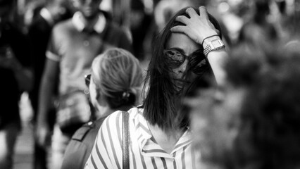 Black and white portrait of a stylish woman adjusting her hair on a busy street in Paris, France