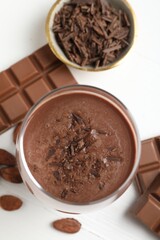 Tasty chocolate milk with shavings and pieces on white table, flat lay