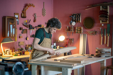 Skilled carpenter carefully prepares handmade wooden furniture parts on sturdy workshop workbench. Custom woodworking, artisanal craftsmanship, order fulfillment, quality control, detailed finishing