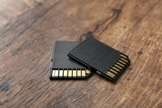 Two SD memory cards on wooden table, closeup